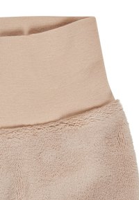 Beiges Fleece-Stoff mit einer weichen, flauschigen Textur und einem beigen Rippstrickbund an der oberen Kante.