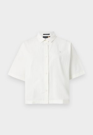 White short-sleeved shirt with a textured fabric, regular collar, and button closure. Small logo on the chest. Relaxed fit design.