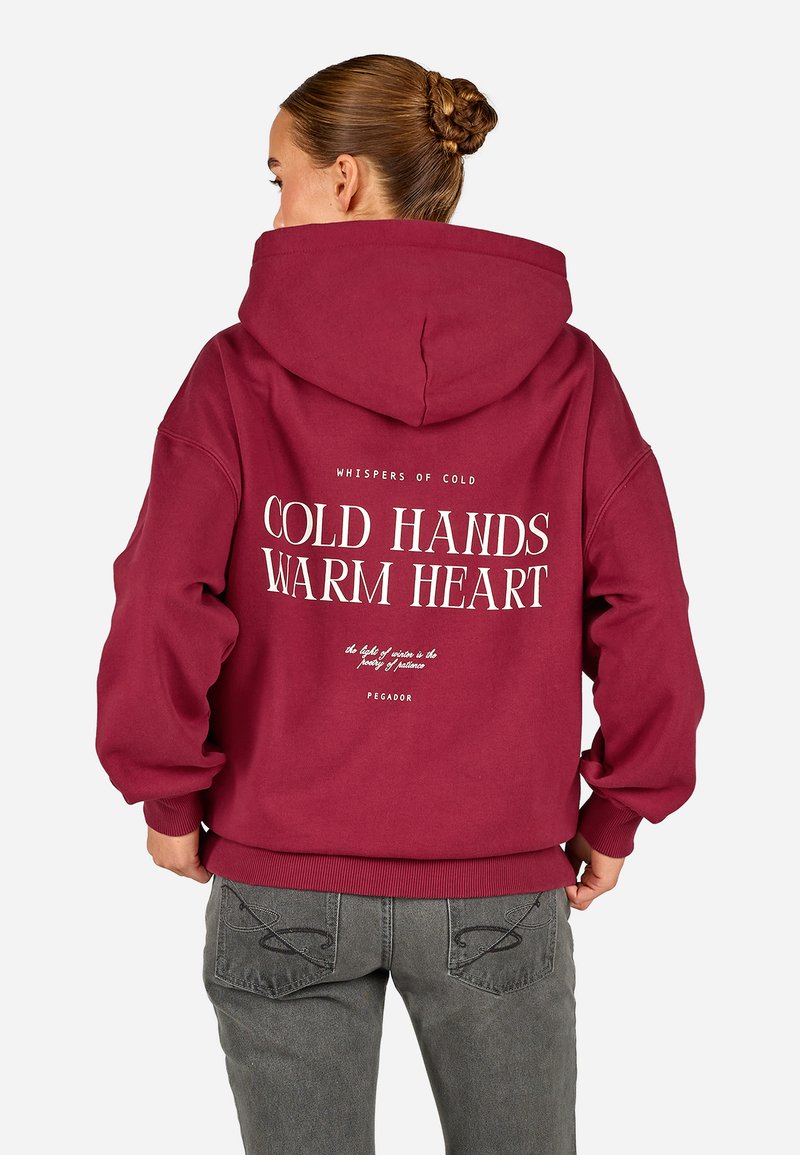 Bordo spalvos gobtuvė su dideliu baltu užrašu "ŠALTOS RANKOS, ŠILTA ŠIRDIS" ir mažesniais tekstais. Medvilnės mišinys, erdvus gobtuvas ir raštuoti rankogaliai.