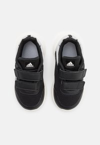 Une paire de baskets Adidas pour tout-petits en noir et blanc avec deux bandoulières velcro, vue de dessus sur un fond blanc.