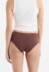 Brązowa prążkowana bielizna z wysokim stanem o gładkiej fakturze, wyposażona w szeroką gumę i minimalne krycie z tyłu.