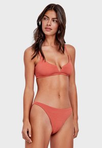 Set bikini color ruggine con una finitura testurizzata. Il top presenta un design a V e spalline regolabili, abbinato a un figurino a vita bassa.