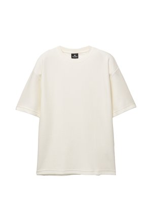 Krátký rukáv, volně střižené krémové tričko vyrobené z texturované látky s kulatým výstřihem a rovnými lemy. Štítek na vnitřní straně límce.