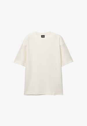 Korte mouwen, losse crème T-shirt gemaakt van textuurstof met een ronde halslijn en een rechte zoom. Etiket aan de binnenkant van de kraag.