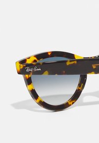 Ochelari de soare în stil țestoasă cu un cadru rotund îndrăzneț, lentile cu degradé și logo-ul emblematic Ray-Ban pe braț. Textură netedă din plastic.