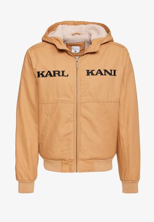 Barna kapucnis dzseki fekete hímzett "KARL KANI" felirattal. Cipzáros záródással rendelkezik, és puha, bézs szőrme bélés biztosítja a kellemes meleget.