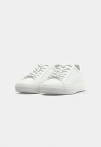 White sneakers with a textured pattern and smooth material. Features round laces, a rubber sole, and a small brand tag on the side.