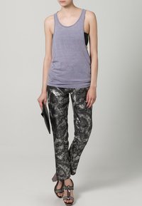Grå tanktopp kombinert med metalliske svarte og sølvfargede mønstrede bukser. Modellen holder en svart clutch. Uformelt fottøy med en blank aksent.