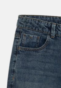 Denim jeans with a light blue wash, featuring a front pocket, belt loops, and contrasting stitching along the waistband and pockets.