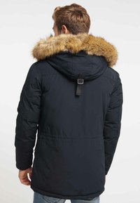 Mörkblå puffjacka med en avtagbar brun pälsfodrad huva, med en svart spänndetalj bak och elastiska ärmmuddar.