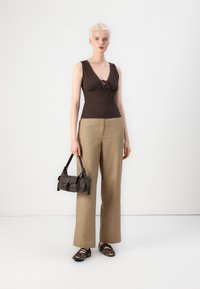 Top marrone senza maniche con pizzo, pantaloni beige a gamba larga, borsa nera con tracolle e scarpe ballerine con stampa leopardata. Design semplice e colori tenui.