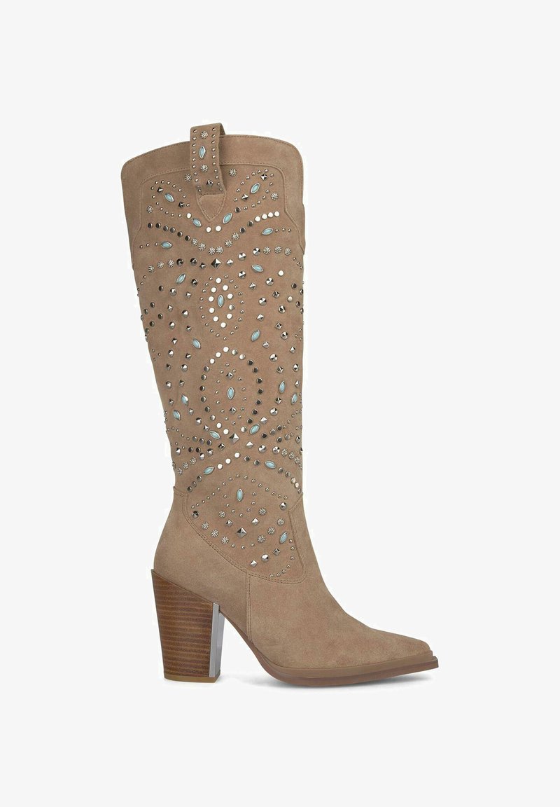 Bota de ante beige hasta la rodilla con punta afilada, decorada con tachuelas plateadas y azules, con un tacón grueso de madera y un tirador.