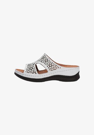 White slide sandal with cutout floral design, brown leather insole, and black textured sole. Features an open-toe and contoured shape.