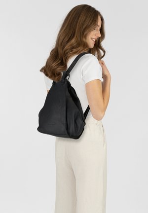 Sac à dos en cuir noir au design souple, avec des bretelles ajustables et une texture lisse. Affiche un style minimaliste sans matériel visible.