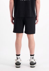 Zwarte katoen shorts met een elastische tailleband, gecombineerd met zwart-witte sneakers met een getextureerd patroon en logo-accenten.
