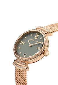 Zlatni ručni sat u ružičastoj boji od mesinga s mrežastim remenom, zelenim teksturiranim brojčanikom, rimskim brojevima i dijamantnim detaljima, s okruglim kućištem i krunicom.