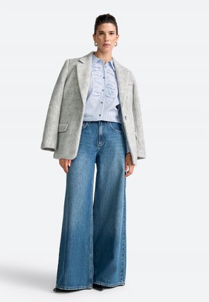 Gray wool-blend oversized blazer, light blue striped button-up shirt, and wide-leg blue jeans with a raw hem, worn with black shoes.