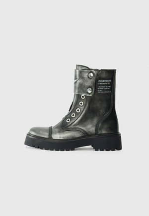 Metallic graue Leder-Ankle Boots mit einer massiven schwarzen Sohle, runder Zehenform, seitlichem Schnallenriemen und silbernen Ösen-Details.