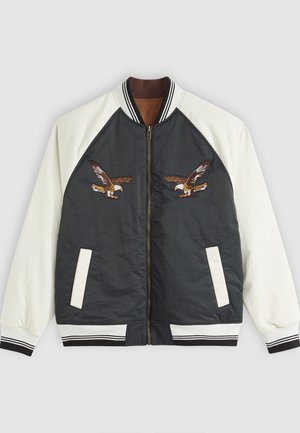 Veste bomber, bleu marine foncé et crème, fermeture éclair, designs d'aigle brodés à l'avant, poignets et ourlet côtelés, poches latérales.