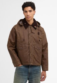 Brown waxed jacket with a corduroy collar, two chest pockets, and drawstring hood. Features a plaid lining and metal hardware accents.