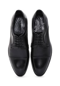 Chaussures habillées en cuir noir avec un design épuré, une texture lisse, des bouts ronds et un laçage traditionnel.