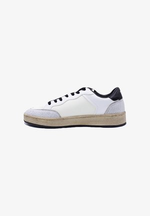 Basket blanche avec lacets et talon noirs, accents en daim gris sur la pointe et le talon, et une semelle épaisse couleur camel, vue de côté sur fond blanc.