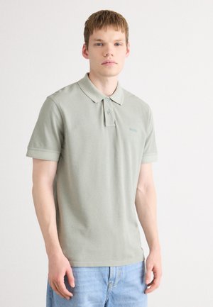 Lysegrønn polo skjorte laget av bomull med klassisk krage, kort ermer og en subtil logo på brystet. Brukt sammen med lyseblå jeans.