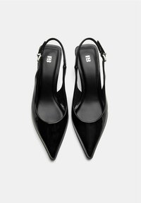 Pantofi cu toc slingback din piele lacuită neagră, cu vârf ascuțit, finisaj neted și curele de gleznă reglabile. Logo-ul este vizibil pe talpă.