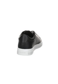 Baskets en cuir noir avec une finition lisse, semelle en caoutchouc blanche, forme arrondie et détail de couture subtil au niveau du talon.