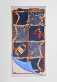 Bufanda de seda con un diseño azul y marrón que presenta cadenas, borlas y un patrón de letras. Detallada con un acento decorativo en rojo y dorado.