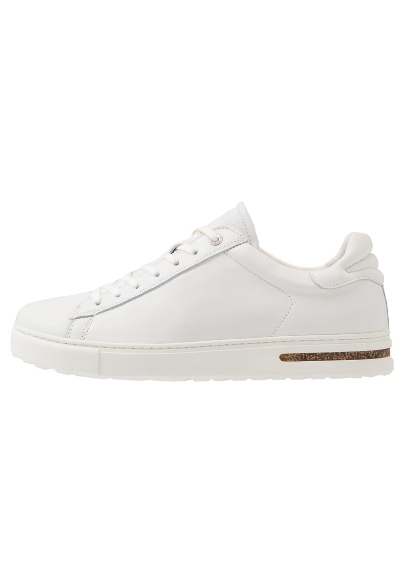 Des sneakers en cuir blanc présentent une finition lisse, un bout rond, un design à lacets et un accent en liège texturé sur la semelle. Légers et minimalistes.