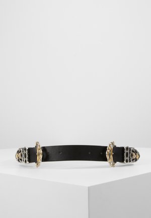 Schwarzer Ledergürtel mit kunstvollen silbernen und goldenen Verzierungen an den Enden, auf einer weißen Oberfläche vor einem grauen Hintergrund präsentiert.