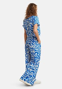 Blau-weiß gemustertes Koordinations-Outfit mit einem lockeren Kurzarmoberteil und weiten Hosen, gefertigt aus einem leichten Stoff mit strukturiertem Finish.