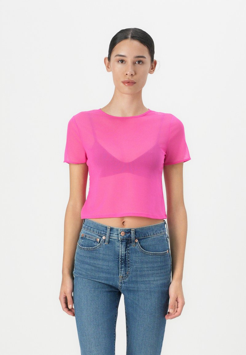 Corta maglietta rosa con una superficie liscia, scollatura rotonda e maniche corte, abbinata a jeans blu a vita alta.