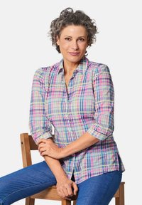 Camicia a quadri leggera con colori pastello in un motivo a griglia, design con bottoni e maniche arrotolate. Abbinata a jeans blu.