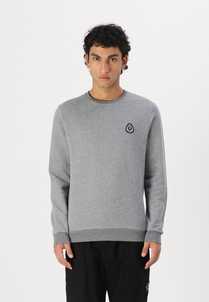 Sweatshirt gri cu mâneci lungi, guler rotund și manșete ribbate. Prezintă o aplicație brodată albastră pe piept. Materialul pare moale.