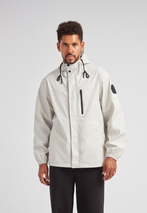 Veste légère à capuche de couleur gris clair avec une poche à fermeture éclair noire sur la poitrine, des poignets élastiques et des cordons réglables sur la capuche.
