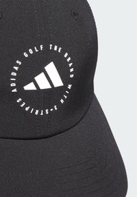Černá golfová čepice Adidas s kulatým bílým logem, které obsahuje text a trojúhelníkovou grafiku, vyrobená z hladké tkaniny se švy.