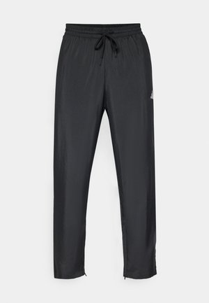 Pantalons de sport noirs avec une taille élastique et un cordon de serrage. Présente une coupe ajustée, une texture douce et des accents zippés au niveau des chevilles.