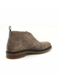 Stivaletti alla caviglia in suede marrone con punta arrotondata e altezza media. Presentano una linguetta, una suola in gomma resistente e dettagli di cucitura discreti.