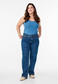 Modelis dėvi šviesiai mėlyną besišalantį marškinėlį ir mėlynus kelnes iki liemens, su tiesia kojų forma. Kelnėse yra priekinė kišenė ir matoma siuvinėjimo siūlė.
