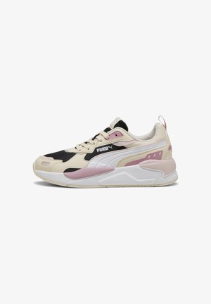 Beige och svart sneaker med rosa detaljer, med en texturerad tygovandel, dämpad sula och distinkt PUMA-logotyp på sidan.