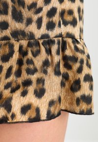 Leopardenmusterstoff mit einem Volantsaum, bestehend aus einer Mischung aus Beige und Schwarz, mit einer weichen Textur und einem subtilen Glanz.