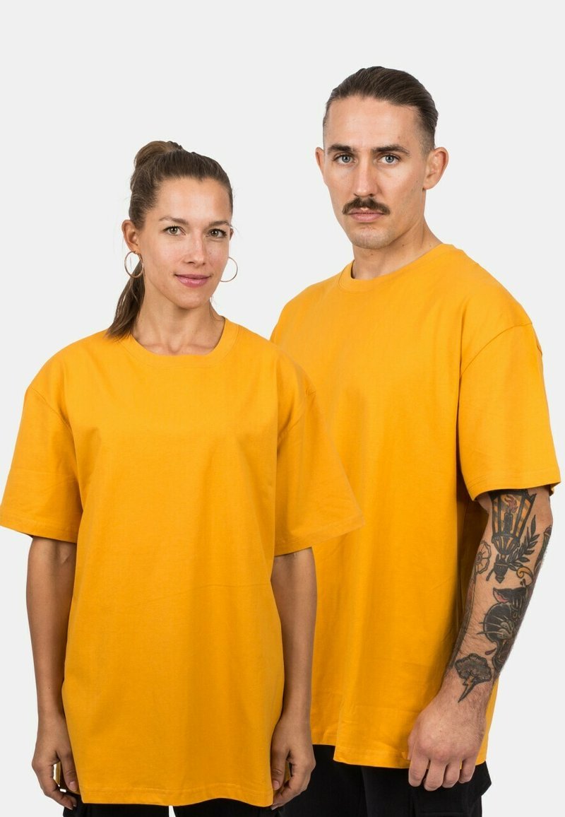Žluté bavlněné trička s krátkým rukávem, oversized střih, kulatý výstřih a jednoduchý design, které mají na sobě dva jednotlivci stojící vedle sebe.