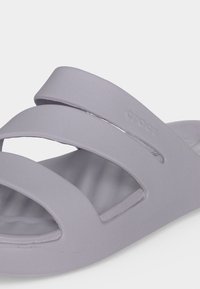 Ανοιχτό γκρι σανδάλι τύπου slip-on με τρεις φαρδιές λουρίδες, επενδεδυμένη σόλα και διακριτικό λογότυπο στην πλαϊνή λουρίδα.
