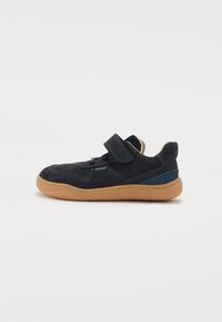 Mørkeblå semsket sneakers med en lys brun gummisåle, med en krok-og-løkke-stropp og blå detaljer på siden.