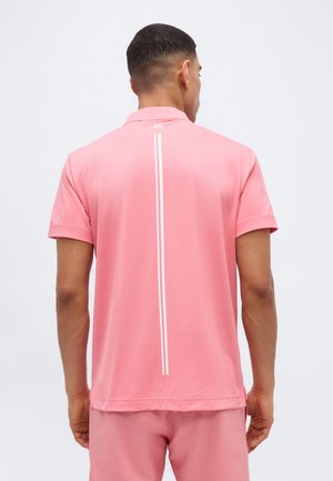 Άνδρας που φοράει ροζ κοντομάνικο πουκάμισο με δύο λευκές κάθετες ρίγες στη μέση της πλάτης, συνδυασμένο με ροζ σορτς που ταιριάζουν.