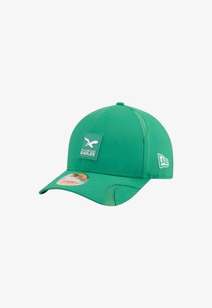 Green baseball cap made of smooth fabric with a stitched front patch featuring a white eagle logo and side accents.