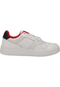 Sneaker bianco in pelle con suola testurizzata, dotata di accenti rossi sul colletto e un tallone nero. Stringhe e perforazioni nell'area della punta.