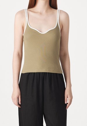 Débardeur côtelé vert olive avec bordure blanche, doté de fines bretelles et d'un col rond plongeant ; associé à un pantalon noir ample.